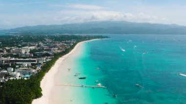 Berrak sularda dalgalar ve tekneler olan tropik beyaz kumsal. Boracay Adası. Filipinler.