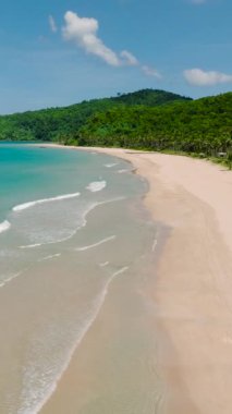 Kumlu sahilde güzel okyanus dalgaları. Nacpan Sahili. Mavi gökyüzü ve bulutlar. El Nido, Palawan. Filipinler. Dikey görünüm.