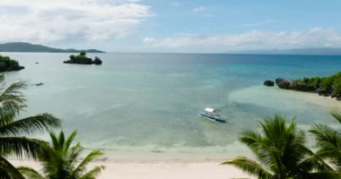 Beyaz sahilde açık deniz suyunda yüzen tekne, Cobrador Adası 'ndaki hindistan cevizi ağaçlarının manzarası. Romblon, Filipinler.