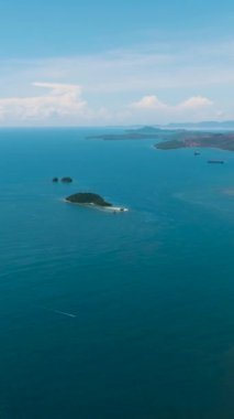 Hava Deniz Burnu: Mavi deniz ve bulutlu gökyüzü. Deniz yüzeyinde tekneler. Mindanao, Filipinler. Dikey görünüm.