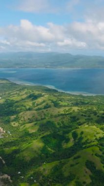 Tropik adadaki yeşil tepeler ve ormanlar. Santa Fe, Tablas, Romblon 'da turkuaz deniz suyu. Filipinler. Dikey görünüm.