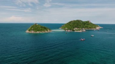 Açık bir gökyüzünün altında turkuaz ve derin mavi denizlerle çevrili kumlu bir şeritle birbirine bağlı ikiz yeşil adalar. Ko Nang Yuan, Tayland.