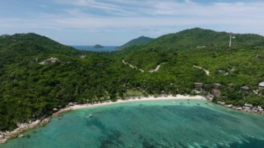 Turkuaz bir körfezi ve parlak bir gökyüzünün altındaki kumlu kıyıları çevreleyen yemyeşil bitkilerle dolu tepeler. Köpekbalığı Körfezi. Koh Tao, Tayland.