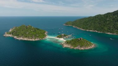 Idyllic körfezi turkuaz suyla çevrili ve temiz bir gökyüzünün altında demirli tekneler var. Nang Yuan, Koh Tao, Tayland.