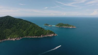 Uçsuz bucaksız mavi okyanusta, sularda yüzen tekneleri olan yeşil kaplı adalar. Koh Tao, Tayland.