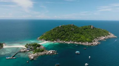 Turkuaz suya uzanan bir iskelesi ve yakınındaki küçük tekneleri olan tropik bir ada. Nang Yuan, Koh Tao, Tayland.