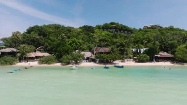 Bereketli tropikal bitki örtüsü ve sakin turkuaz sularda yüzen teknelerin olduğu sahile. Koh Tao, Tayland.