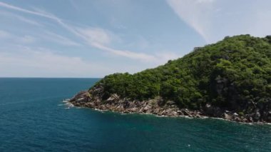 Bereketli yeşil tepeler ve açık gökyüzünün altındaki derin mavi okyanus tarafından çerçevelenmiş Rocky kıyı şeridi. Koh Tao, Tayland.