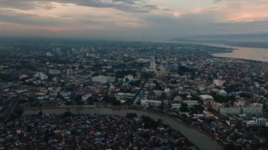Davao City: Alacakaranlıkta bir sahil şehri. Bulutlu gün batımı ve gökyüzü. Mindanao, Filipinler.
