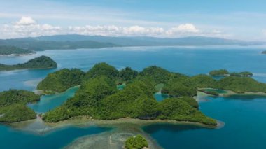Lagünleri olan küçük adaları olan güzel Tinago Adası. Mavi gökyüzü ve bulutların altındaki mercan resifleri. Mindanao, Filipinler.