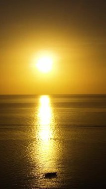 Sarı günbatımı arkaplanlı bir tekne denizin üzerinde akıyor. Bantayan, Cebu, Filipinler. Dikey görünüm.