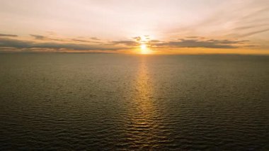 Altın gün batımı turuncu gökyüzü ve dağınık bulutlarla sakin deniz yüzeyine yansıyor. Koh Tao, Tayland.