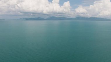 Uzak adaları ve gökyüzünde dramatik bulut oluşumları olan turkuaz deniz manzarası. Ko Pha Ngan, Tayland.