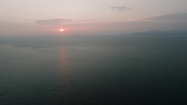 Güneş ufukta yavaşça batarken pastel renkli gökyüzünün altında sakin bir okyanus. Ko Pha Ngan, Tayland.