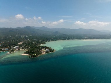 Turkuaz suların ve berrak gökyüzü olan bir dağ zemininin yer aldığı manzaralı kıyı şeridi. Ko Pha Ngan, Tayland.