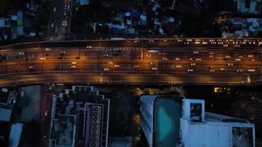 Yoğun arabalı, ulaşımlı ve gece lambalı ticari binalı otobanın en üst görüntüsü. Bangkok, Tayland.