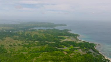 Dalgalanan yeşil tepeleri ve durgun turkuaz suları olan uzak bir kıyı şeridi. Santa Fe, Tablo, Romblon, Filipinler.
