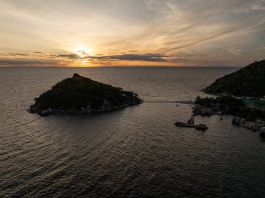 Gün batımında sakin denizle çevrili küçük adalar, iskele ve canlı gökyüzü. Koh Tao, Tayland.