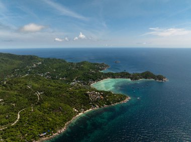 Bereketli tepeleri olan kıyı köyü ve parlak mavi gökyüzünün altında turkuaz bir koy, dingin doğal güzelliği sergiliyor. Koh Tao, Tayland.