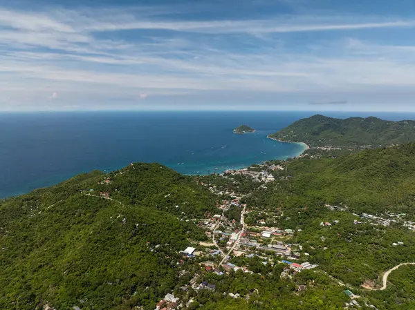 Bereketli yeşil tepeleri olan kıyı manzarası, uzakta küçük adalar ve turkuaz suların üzerinde açık mavi bir gökyüzü. Koh Tao, Tayland.