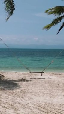 Beyaz kumun üzerinde sallanan iki palmiye ağacının ve turkuaz deniz sularının olduğu sakin bir tropikal plaj. Haad Yuan Sahili. Ko Pha Ngan, Tayland.