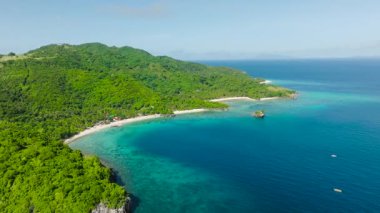 Berrak, güneşli bir gökyüzünün altında turkuaz suyu ve yemyeşil bir çevresi olan tenha bir tropikal koy. Cobrador Adası, Romblon, Filipinler.