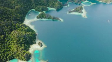 Kireçtaşı kayalıklarıyla çevrili lagünlerin manzarası. Koron, Palawan, Filipinler 'deki mavi denizin üzerinde turist tekneleri. 5 bin..