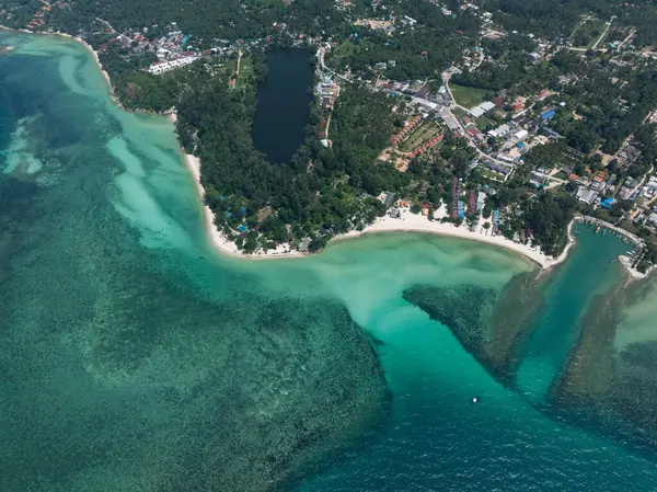 Turkuaz deniz bereketli yeşil sahili çevreleyen dağınık binalar ve kumlu plajlar. Ko Pha Ngan, Tayland.