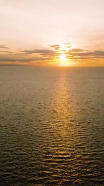 Altın gün batımı turuncu gökyüzü ve dağınık bulutlarla sakin deniz yüzeyine yansıyor. Koh Tao, Tayland.