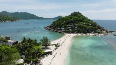 Turkuaz suyla çevrili güneş şezlongları ve şemsiyeleri olan beyaz kumsal. Nang Yuan, Koh Tao, Tayland.