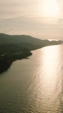 Manzaralı altın güneş ışığı ön planda kıyı silueti ile denize yansıyor. Ko Samui, Tayland.