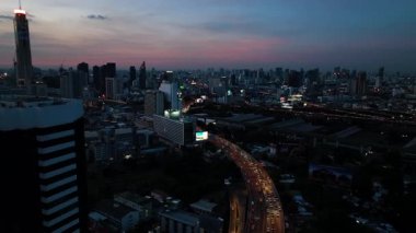 Bangkok 'taki modern binalar ve kuleler, trafik ve arabalarla otoyolların üzerindeki renkli gökyüzü. Bangkok, Tayland.