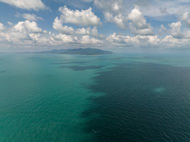 Engin turkuaz deniz manzarası, gölgeli yamalar, uzak dağlar ve beyaz bulutlu mavi bir gökyüzü. Tayland, Koh Samui.