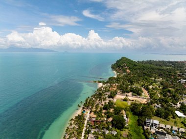 Tropikal bitki örtüsü, kumlu plajlar ve güneşli bir gökyüzünün altında sakin turkuaz sulara sahip ada manzarası. Koh Samui, Tayland.