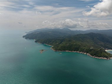 Zümrüt suları, yemyeşil tepeler ve açık mavi gökyüzünün bulunduğu tropik kıyı şeridi. Ko Pha Ngan, Tayland.