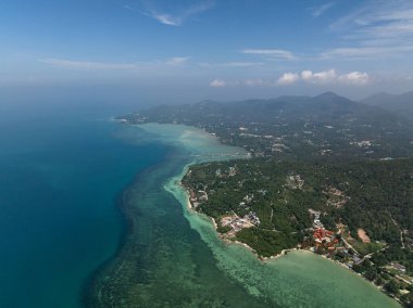 Turkuaz suları, yeşil tepeleri ve ufka uzanan berrak gökyüzü ile panoramik bir sahil manzarası. Ko Pha Ngan, Tayland.
