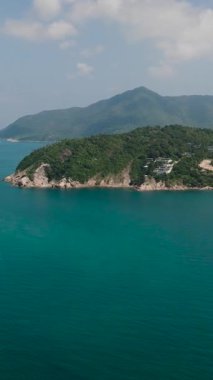 Açık deniz, ormanlık kıyı şeridi ve berrak bir gökyüzünün altında sakin sular. Ko Pha Ngan, Tayland.