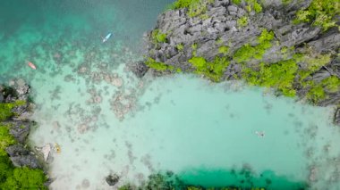 Big Lagoon 'da şeffaf deniz suyu ve Miniloc Adası' nda kanoları var. El Nido, Palawan. Filipinler.
