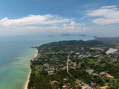 Arka planda tepeler ve ön planda turkuaz su bulunan bir sahil kasabasının havadan görünüşü. Koh Samui, Tayland.