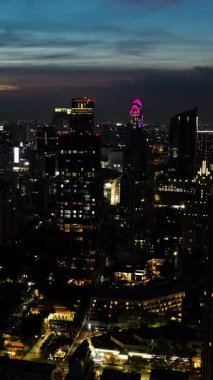 Gökdelenler gökyüzünü aydınlatıyor, yüksek binalar gece gökyüzüne karşı aydınlanıyor. Bangkok, Tayland.
