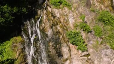 Akan su, yeşil yapraklarla çevrili yosun kaplı kayaların üzerinde yavaşça akıyor. Na Mueang Şelalesi. Ko Samui, Tayland.