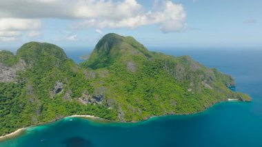 Yoğun yeşil bitki örtüsü ve turkuaz denizle kaplı canlı bir ada. Cadlao Adası. El Nido. Palawan, Filipinler.