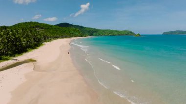 Sahilde sonsuz bir yalnızlık ve huzur var. Kristal berrak su, el değmemiş kumsalla birleşir. Nacpan Plajı, El Nido, Filipinler.