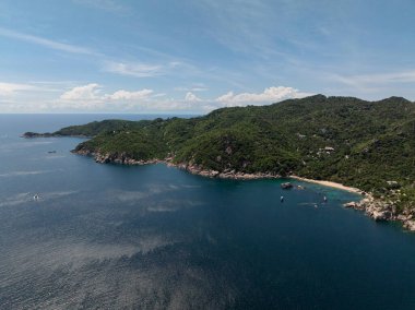 Turkuaz su, yeşil tepeler ve dağınık botlarla sakin bir atmosfer içeren el değmemiş bir koy. Koh Tao, Tayland.