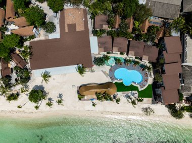 Havuzu ve beyaz kumlu sahil ve turkuaz deniz boyunca sıralanmış palmiye ağaçları olan bir tatil köyü manzarası. Rin Nai Sahili. Ko Pha Ngan, Tayland.