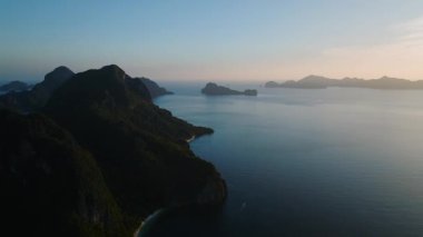Yeşilliklerle kaplı yüksek bir uçurum ön planda hüküm sürüyor. El Nido, Palawan, Filipinler 'de karanlık gökyüzü.