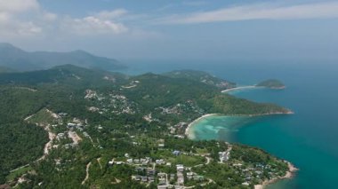 Ormanlık tepelerle çevrili turkuaz ambarlar ve küçük yolları olan dağınık yerleşim alanları açık okyanusa karışıyor. Ko Pha Ngan, Tayland.