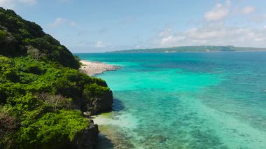Turkuaz su yeşil kayalıkları kucaklıyor ve parlak güneşli bir gökyüzünün altında kumlu plajlar var. Boracay Adası, Filipinler.