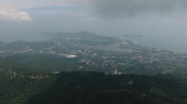 Şehir ve kıyı şeridi, yeşil tepeler ve bulutlu gökyüzü ile çevrili. Ko Samui, Tayland.