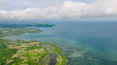 Parlak mavi suları, yemyeşil kıyıları ve parlak bir ufku olan çarpıcı bir deniz manzarası. Tablolar, Romblon, Filipinler.